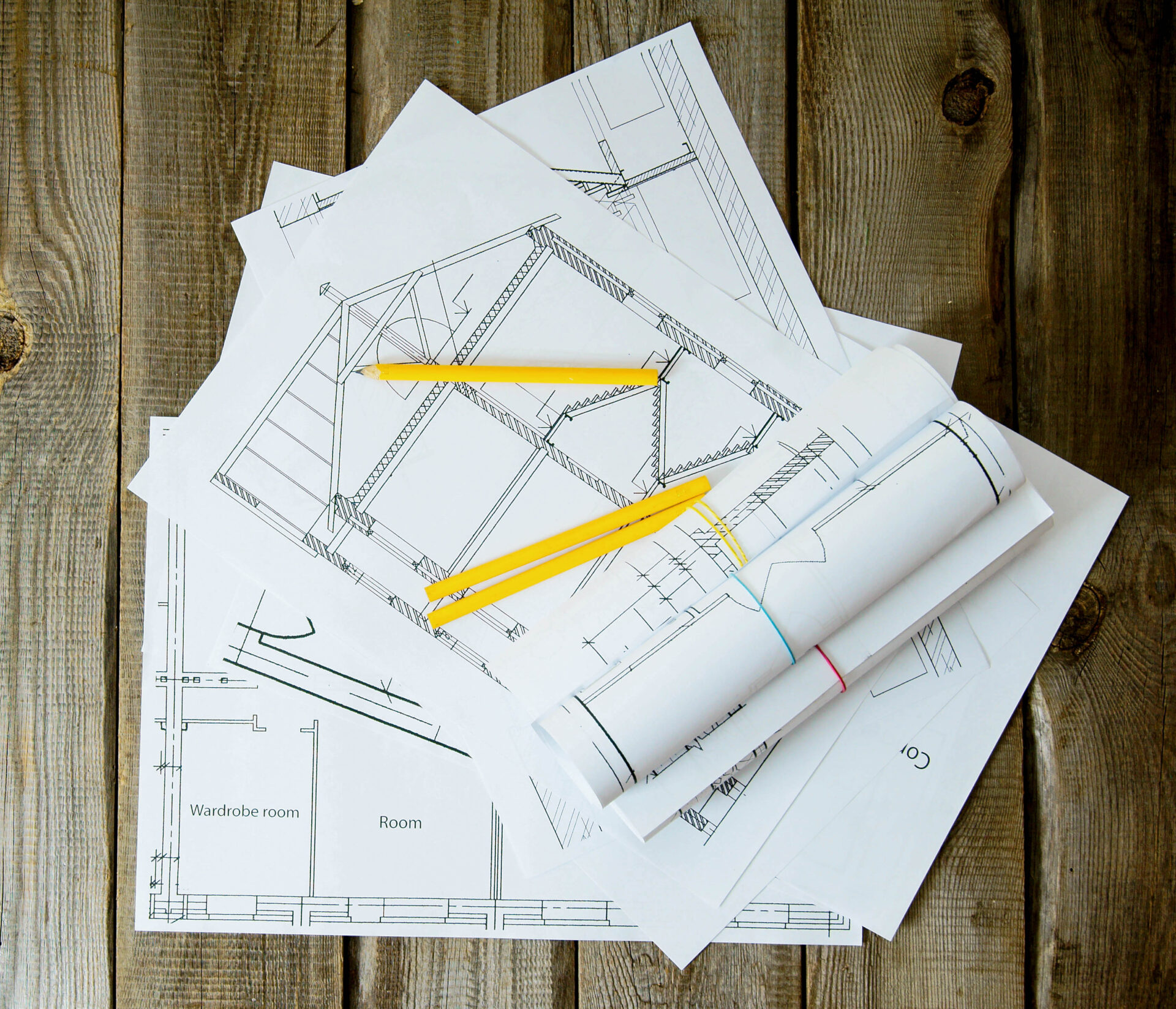 We build a building. House construction. Many drawings for building and pencils on old wooden background.